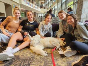 Students huddle around a therapy dog visiting in TLCC.